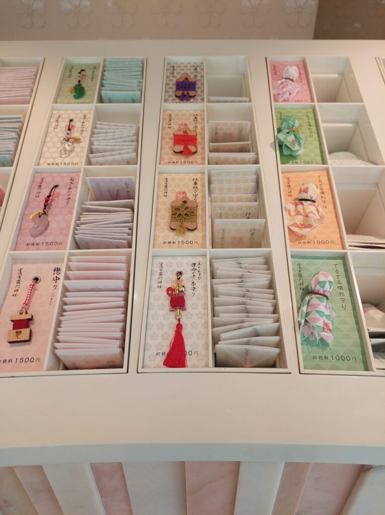 Colorful omamori charms at Kamado Shrine — magatama-shaped and teru-teru-bozu designs bringing good luck and love.