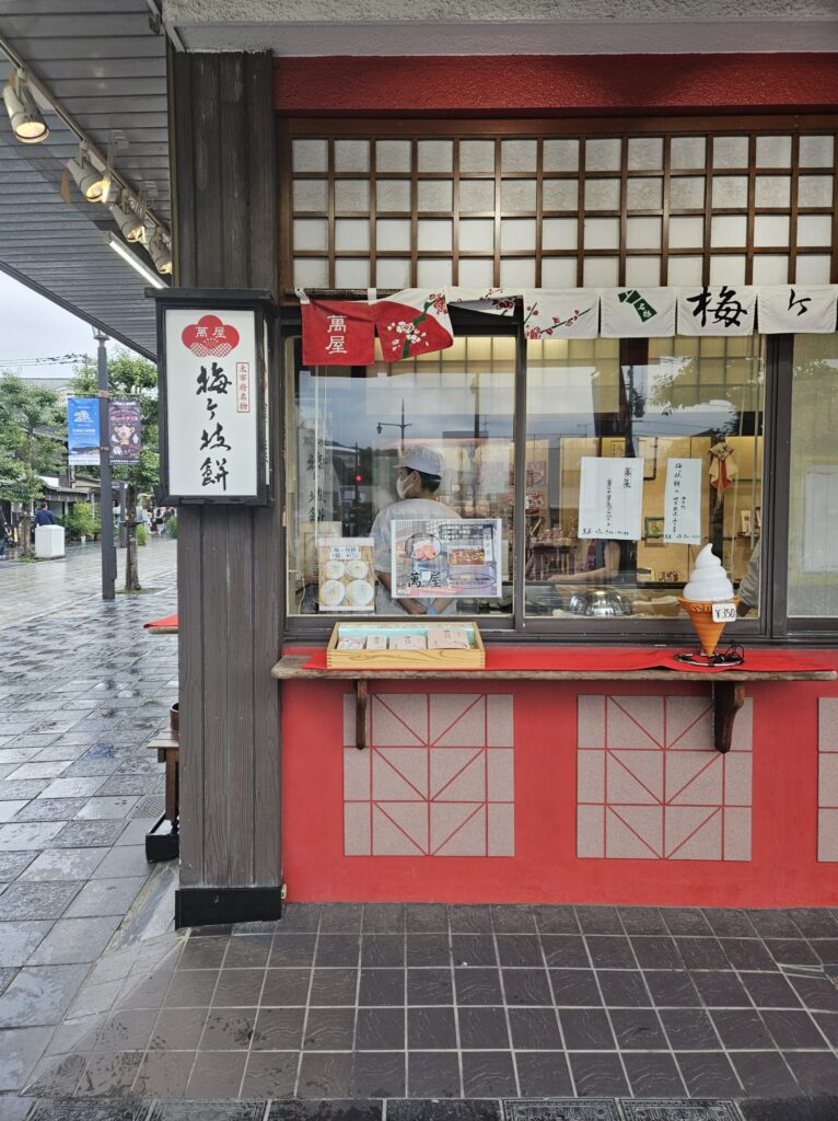 Exterior of Yorozuya, the first Umegae Mochi shop near Dazaifu Station, located at the entrance of the approach to Dazaifu Tenmangu Shrine — a cozy, well-loved shop with the aroma of freshly grilled mochi.