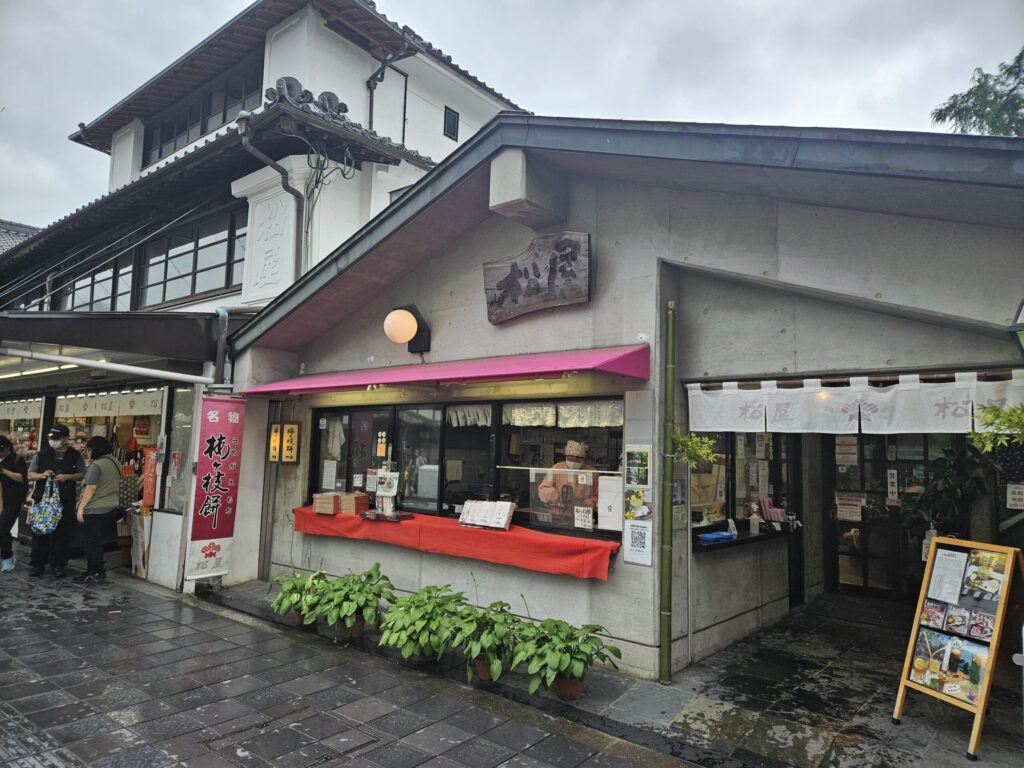 Exterior of Matsuya, a long-established Umegae Mochi shop on the approach to Dazaifu Tenmangu Shrine. The café-style storefront offers a calm atmosphere where visitors can enjoy Umegae Mochi with matcha.