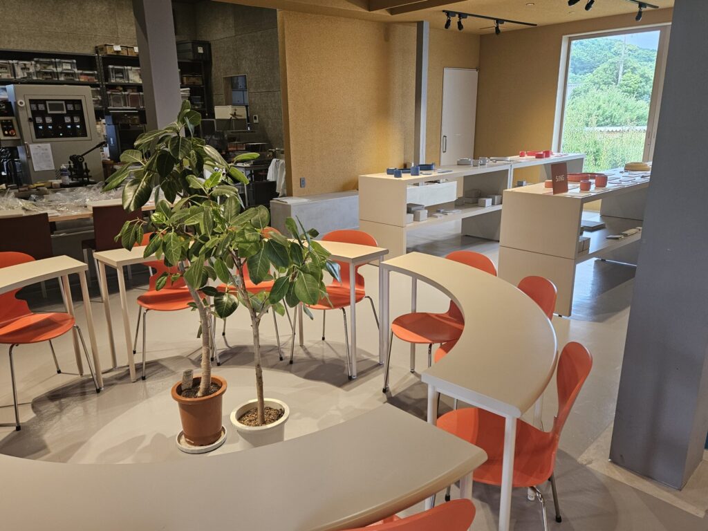 Interior of Café Si near Kamado Shrine, featuring an artistic round table and bright orange chairs.