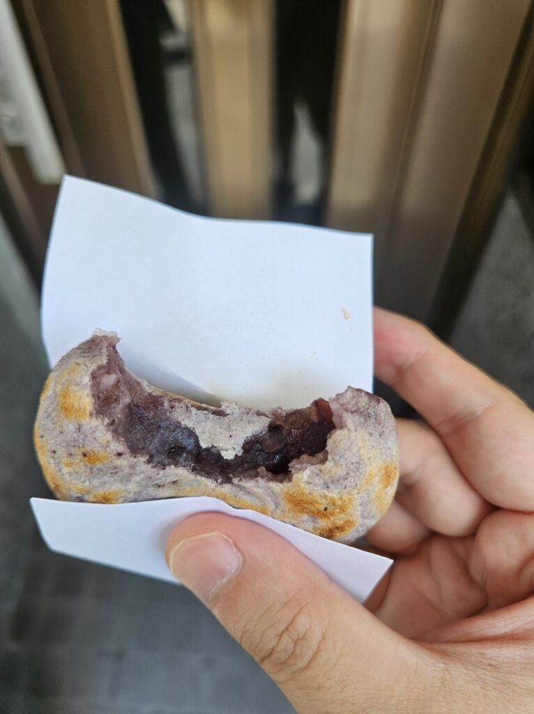 Close-up of the limited purple Umegae Mochi, bitten to show the sweet red bean filling inside.