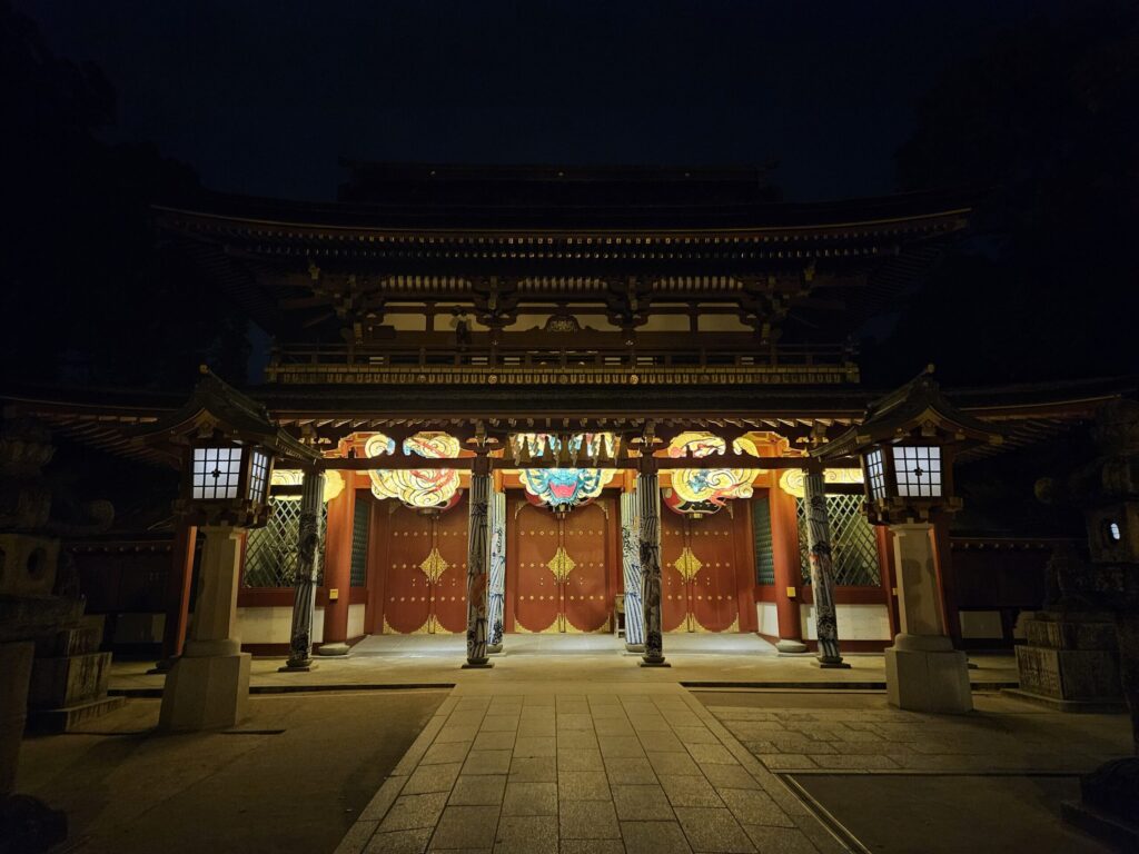 Distant night view of the glowing Flying Dragon Nebuta lighting up the grounds of Dazaifu Tenmangu Shrine.