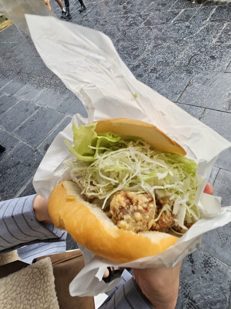 Close-up of the famous Dazaifu Burger from Chikushian, featuring crispy fried chicken, tartar sauce, and plum sauce.