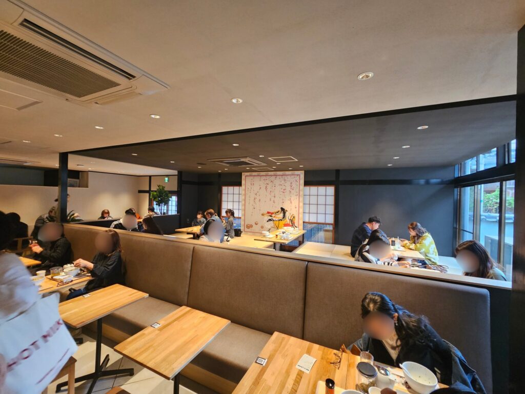 Interior of nana’s green tea Dazaifu Sando Café with sunken kotatsu tables and guests relaxing in a calm, cozy setting.