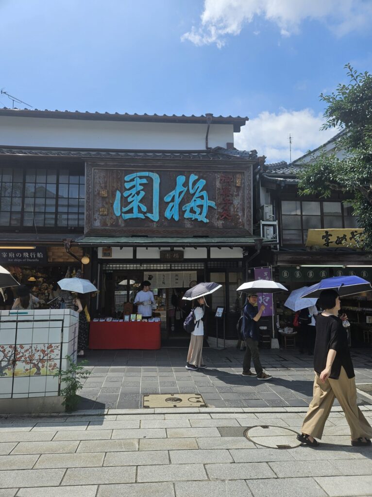 Exterior of Baien, a long-established wagashi shop in Dazaifu, with a wooden Japanese signboard featuring green characters reading “Baien.”