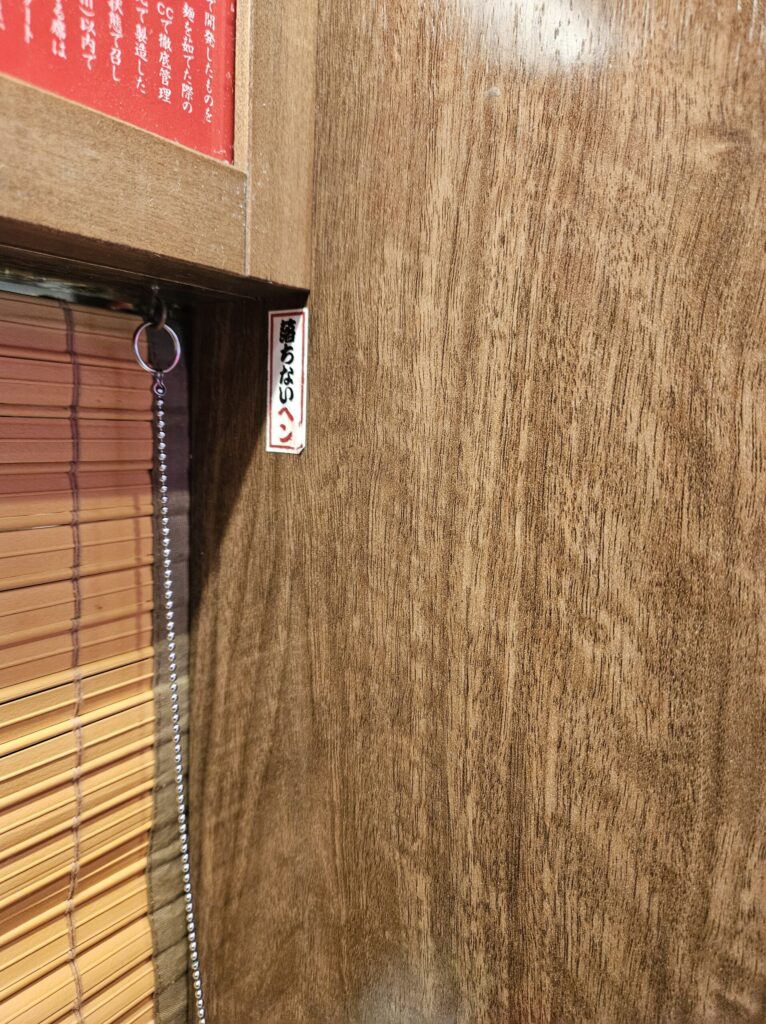 Ichiran Dazaifu Sando Ten interior sign explaining the lucky “Ochinal Pen” that symbolizes not failing exams.