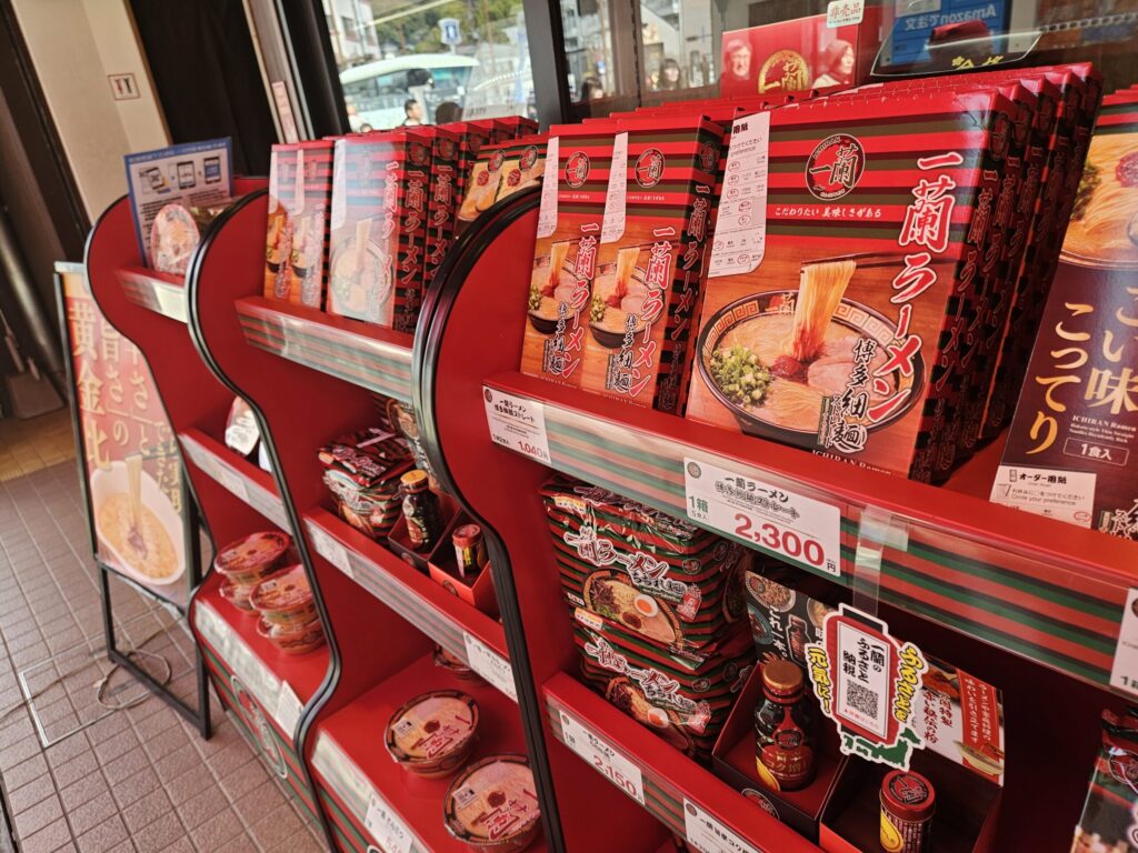Ichiran Dazaifu Sando Ten souvenir corner near the exit, displaying instant ramen and other take-home products on shelves.