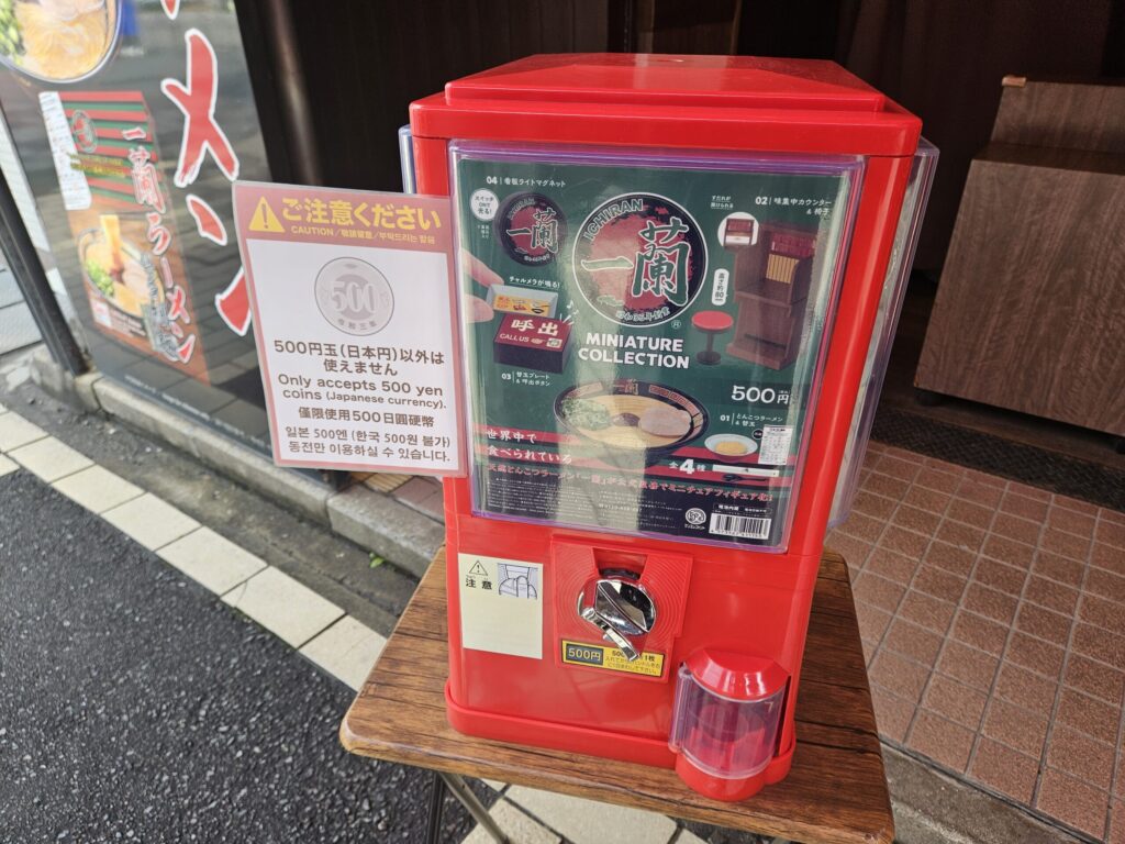 Ichiran Dazaifu Sando Ten capsule toy machine near the exit offering ramen-themed merchandise.